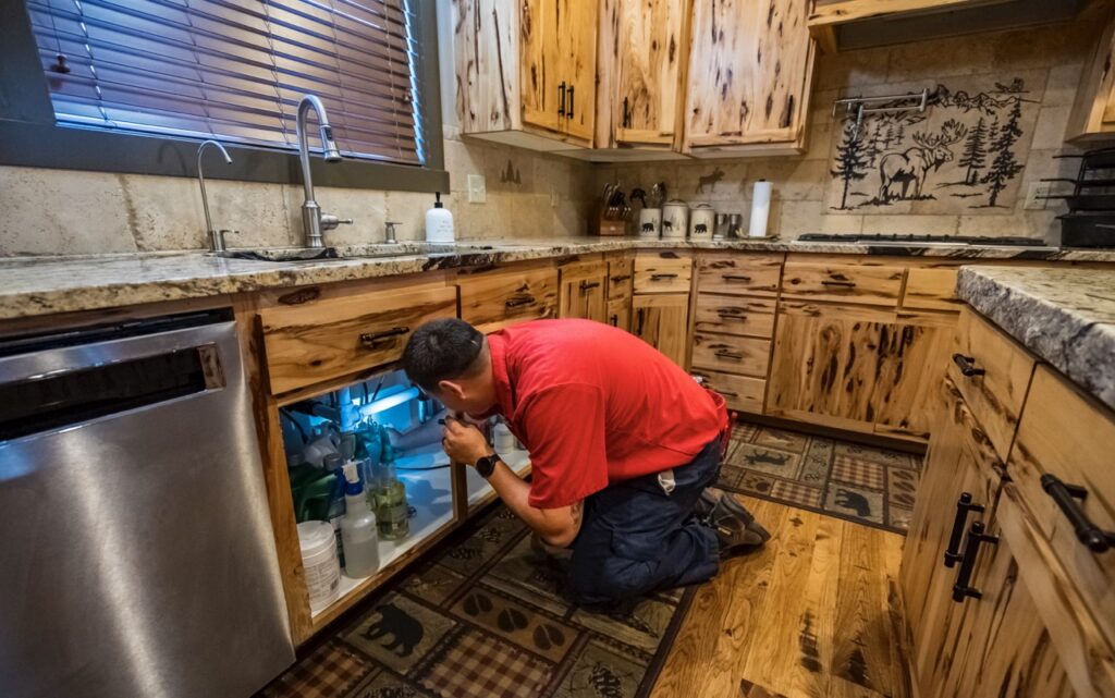 Technician preforming sewer and drain services in Rexburg home.