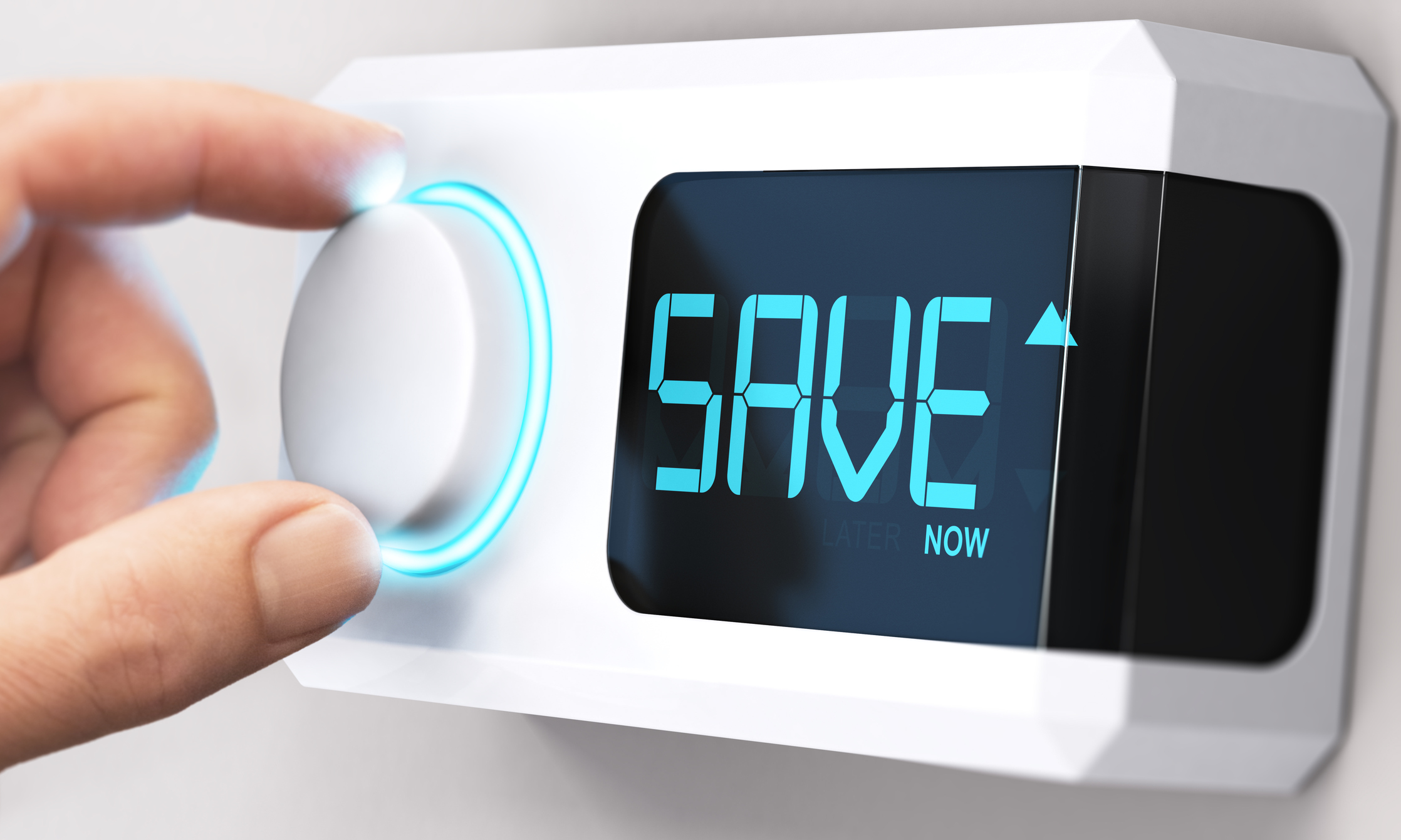 Hand turning a thermostat knob to increase savings by decreasing energy consumption. Thermostat digital screen reads "SAVE Now"